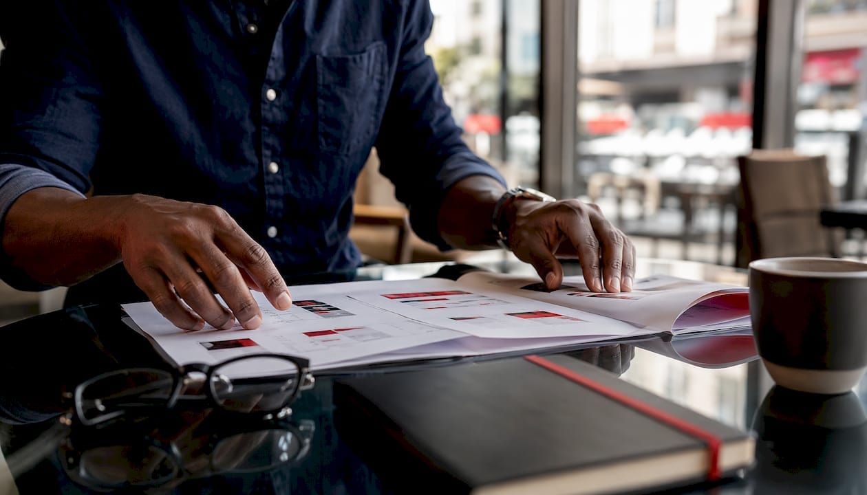 Hands arranging marketing pilot plan documents on desk